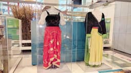 Two women's outfits on mannequins in a display case, one with a red skirt and the other with yellow.