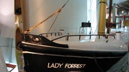 The red and black hull of the Lady Forrest is suspended next to the walkway.