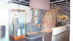 A replica conning tower of a submarine towering above the gallery floor. It is covered in a thick layer of encrustation.