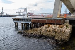 A large brown rock formation in front of the harbour's edge.