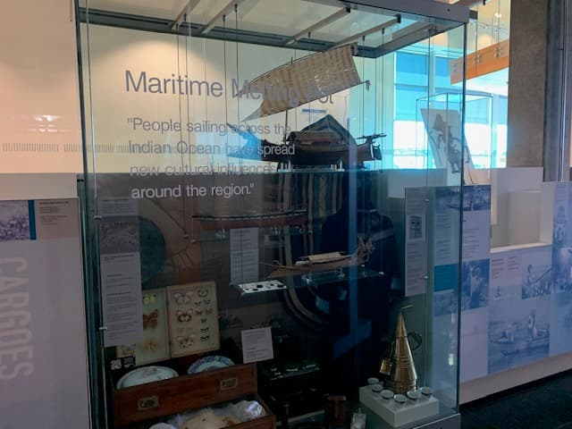 A glass display case featuring objects such as a coffee pot, plates and butterflies.