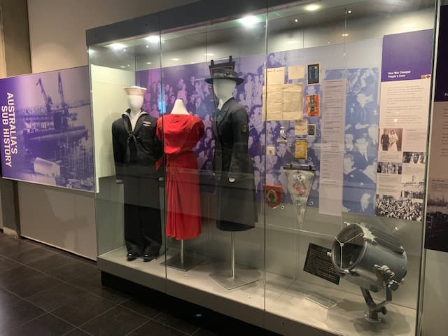 Clothing from World War II including a sailor's uniform and a red dress.