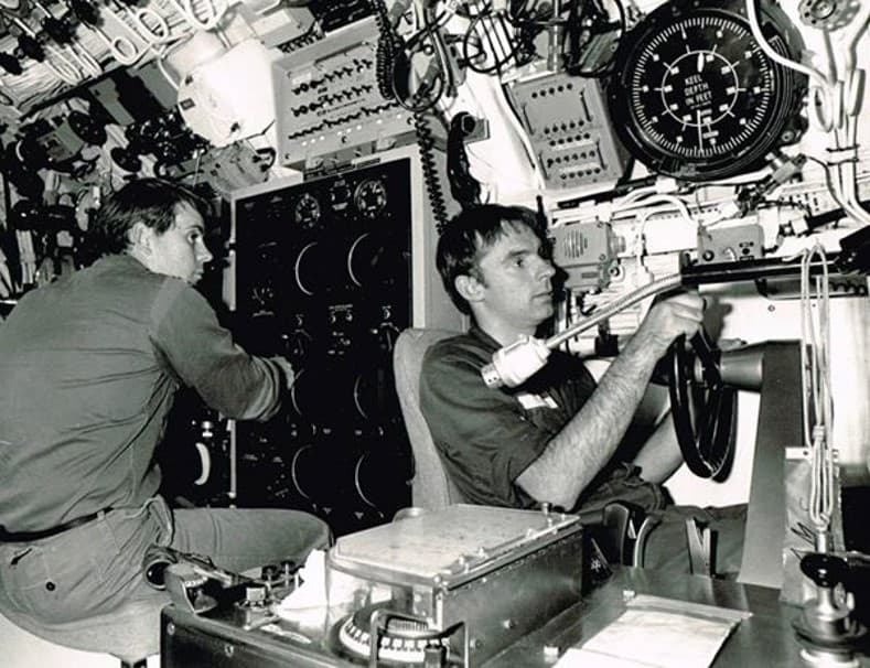 One crew is hunched over a large wall panel of dials while another sits tightly gripping the sub's steering wheel.
