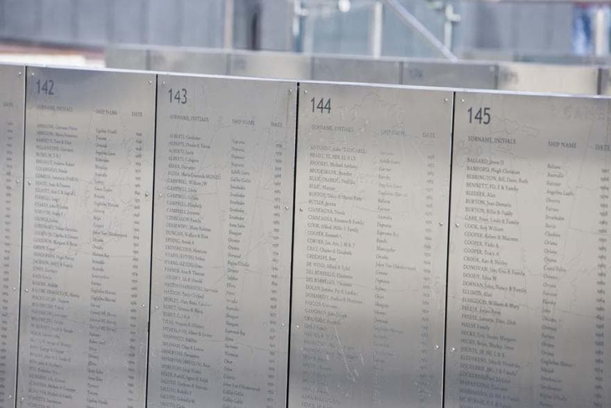 A low wall made up of metal panels engraved with names and numbers.