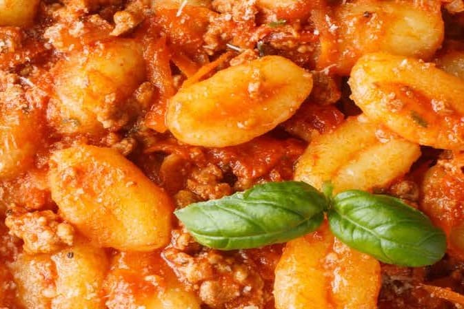 Gnocchi in a tomato mince sauce, garnished with bright green basil leaves