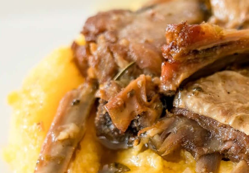 cooked, browned meat and bones served on top of yellow cooked polenta