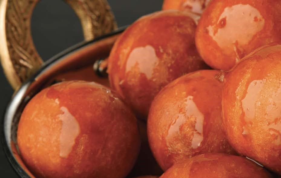 glazed shiny balls of fried dough in a shiny brass dish