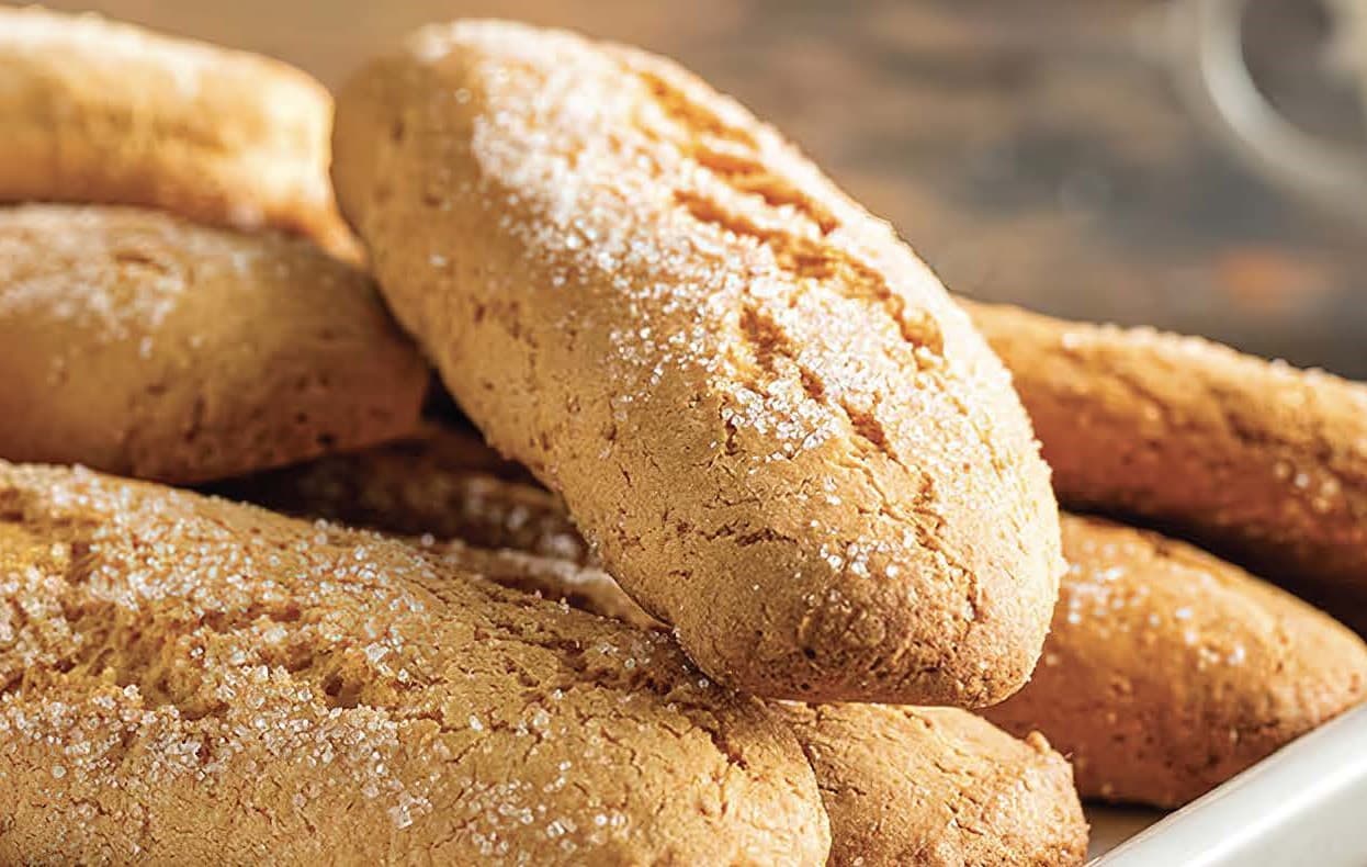 Golden brown biscuits dusted with sugar sit on a white platter